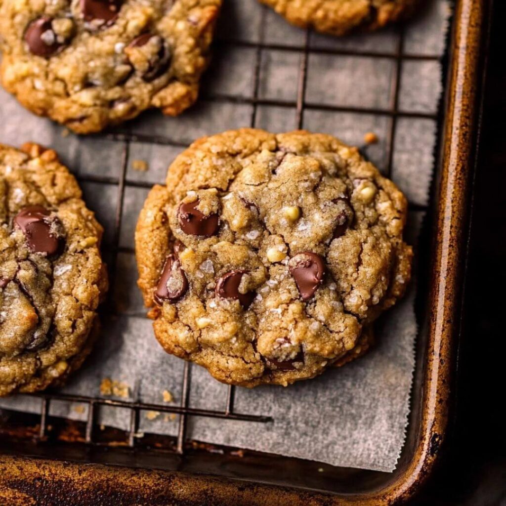 Close-up of freshly baked cowboy cookies with chocolate chips and oats on a wire rack lined with parchment paper