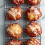Golden brown air fryer apple fritters drizzled with sweet glaze cooling on a wire rack