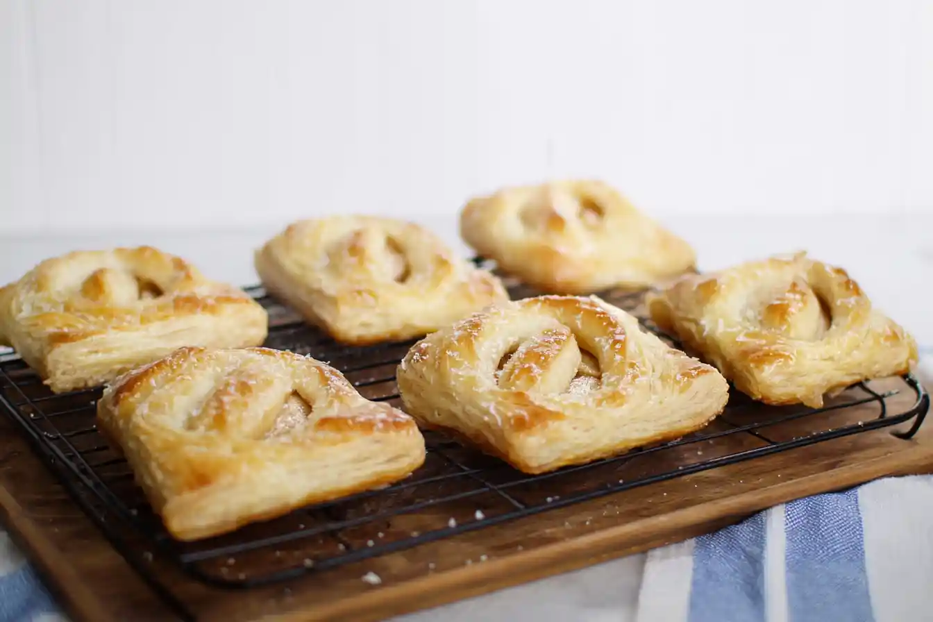 A golden-brown quick 3 ingredient apple danish is presented on a clean white surface, showcasing its flaky pastry and visible apple filling.