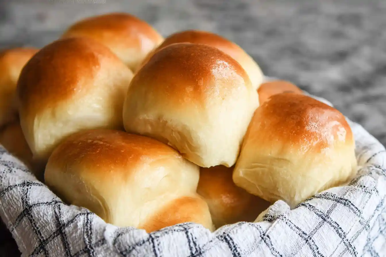 A close-up view of several golden-brown, freshly baked Dinner Rolls in a basket.