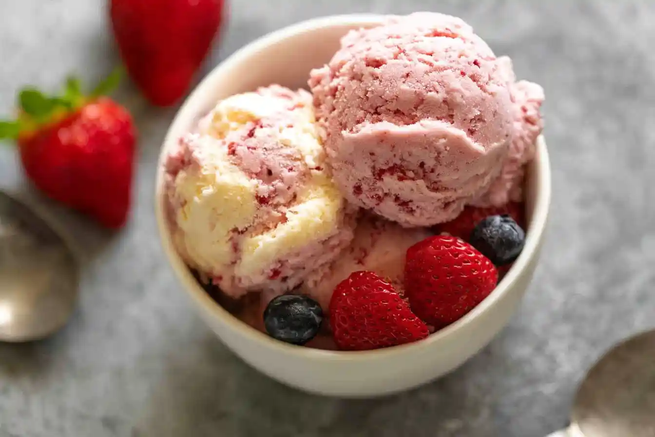 A vibrant bowl of homemade Fruity No-Churn Ice Cream, generously topped with fresh berries like strawberries, blueberries, and raspberries.