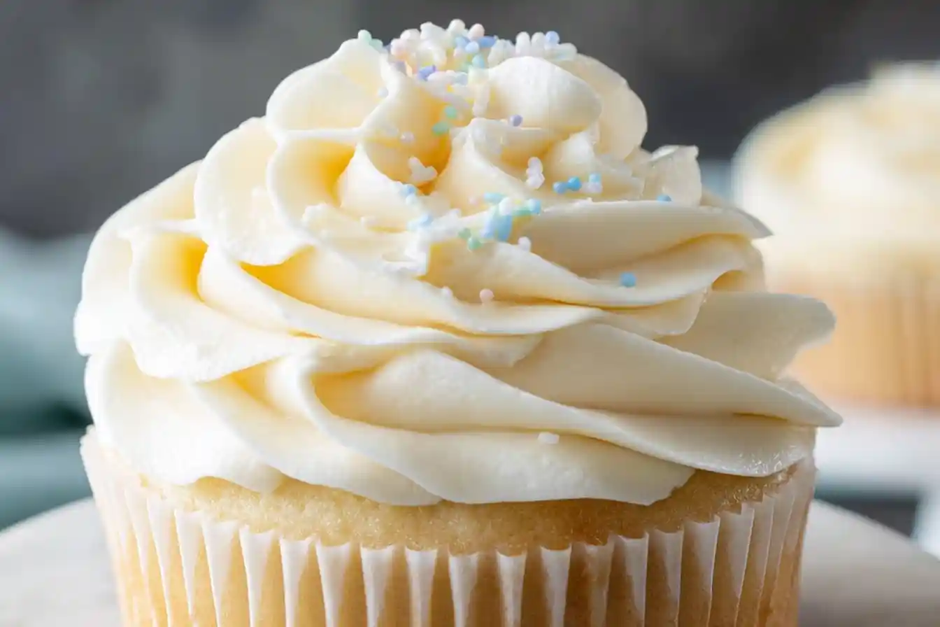 A perfectly piped swirl of creamy vanilla buttercream frosting sits atop a cupcake, ready to be enjoyed.