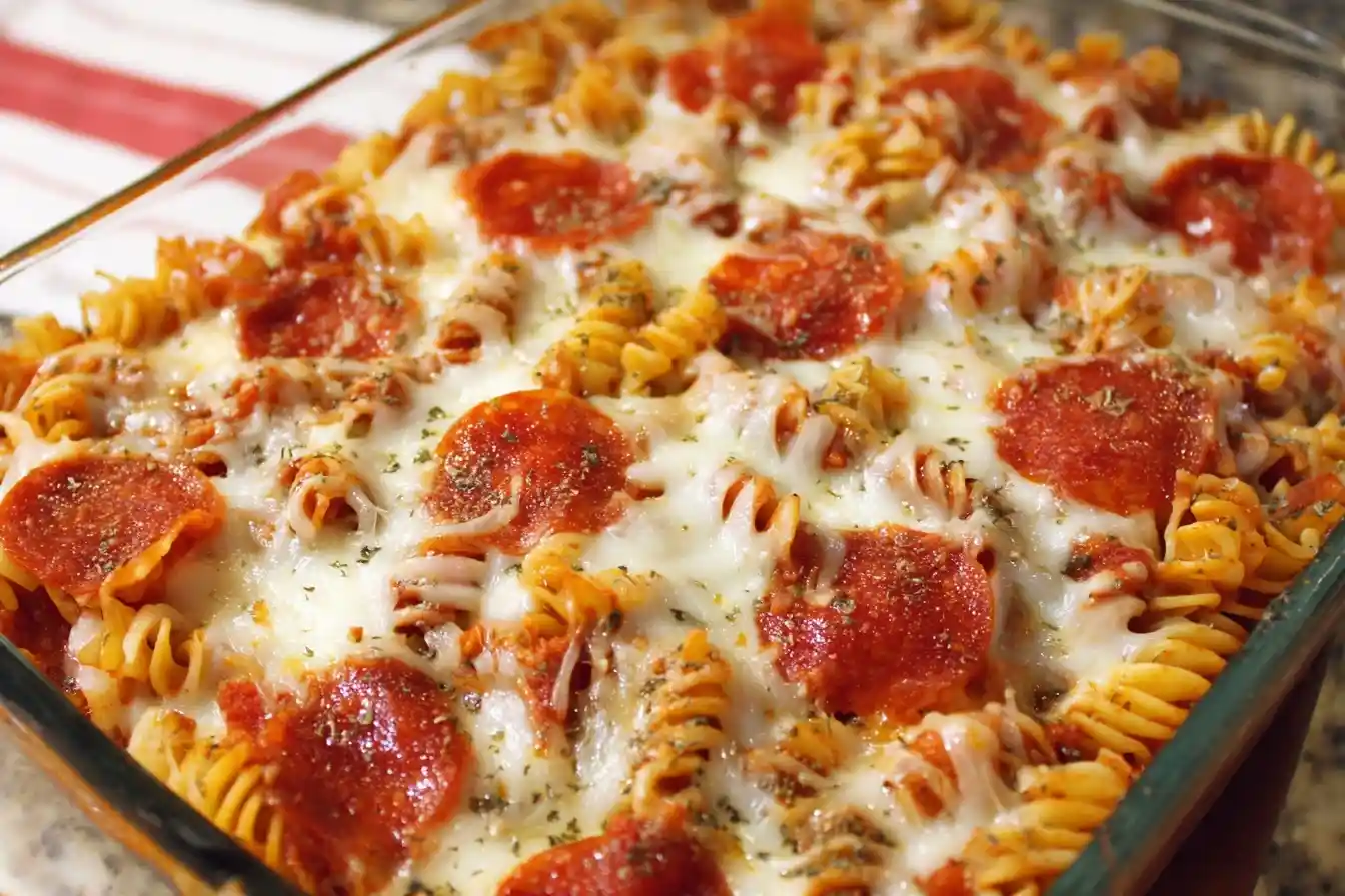 A close-up of a cheesy Pizza Casserole with rotini pasta, pepperoni, and melted mozzarella cheese in a glass baking dish.