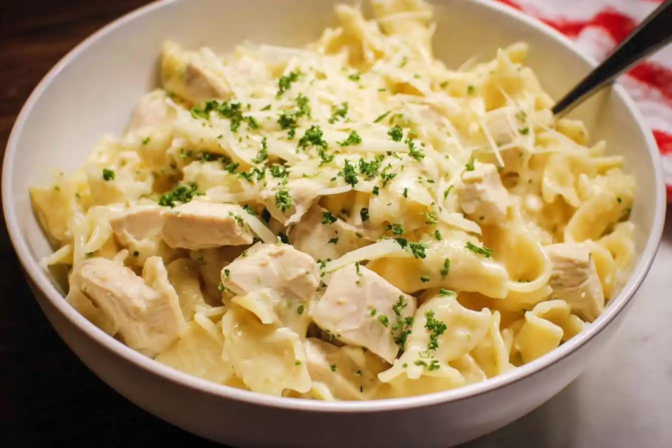 A close-up of a white bowl filled with creamy {{ $('Fetch Recipe Data').first().json["Main Keyword"] }}, topped with parmesan cheese and fresh parsley.
