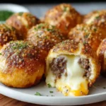 A plate of golden-baked cheeseburger bombs, with one cut open to reveal a gooey, melted cheese and ground beef filling.