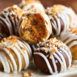 Close-up of carrot cake truffles drizzled with white icing and crushed nuts, showing the moist spiced cake interior.