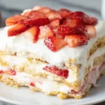 Close-up slice of Strawberry Icebox Cake with layers of graham crackers, whipped cream, and fresh strawberries.