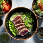 Overhead shot of a fresh Seared Tuna Poke Bowl with sesame-crusted tuna, edamame, and cucumber slices.