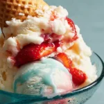 Close-up of a strawberry sundae featuring pastel ice cream, fresh berries, and an overturned waffle cone.