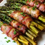 Roasted bacon wrapped asparagus bundles arranged on a white plate and garnished with parsley.