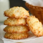 A stack of golden brown coconut macaroons resting on white parchment paper.