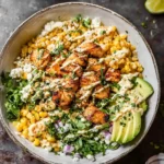 A hearty Chicken Street Corn Bowl topped with grilled chicken, corn, avocado, feta, cilantro, and a creamy drizzle.