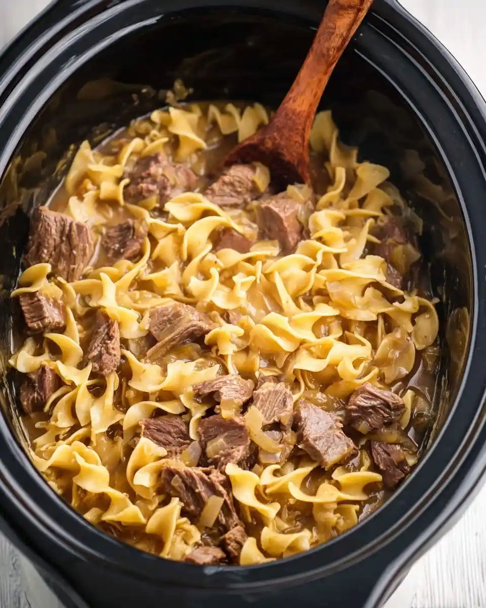 Wooden spoon stirring a hearty batch of {{ $('Fetch Recipe Data').first().json["Main Keyword"] }} in a black pot.