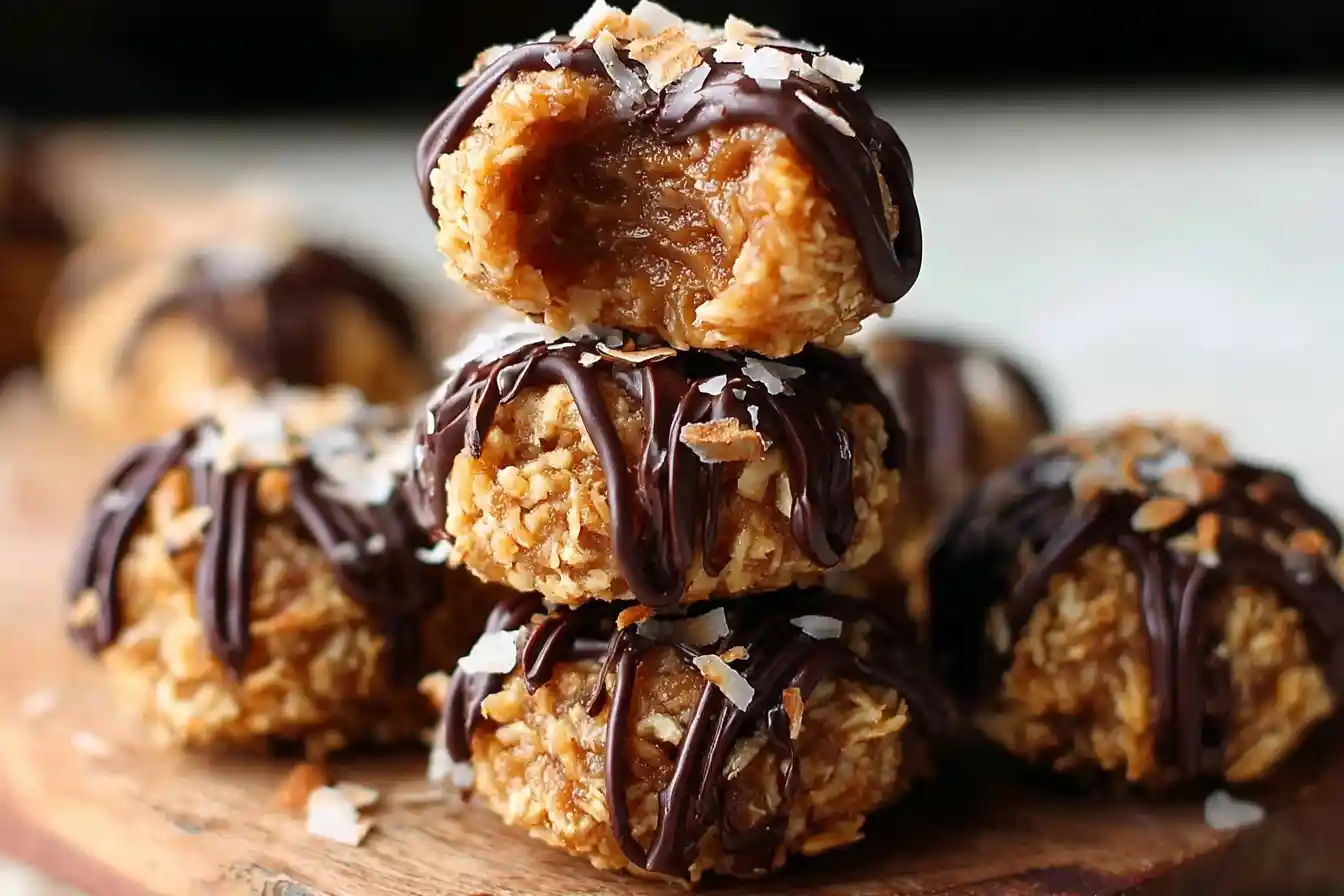 Stack of homemade Samoa cookies on a wooden board with a bite taken out of the top one showing the chewy coconut center.