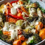 A colorful roasted vegetable bowl featuring broccoli, carrots, Brussels sprouts, and a creamy tahini dressing.