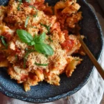 A serving of {{ $('Fetch Recipe Data').first().json["Main Keyword"] }} in a dark bowl with breadcrumbs and fresh basil.