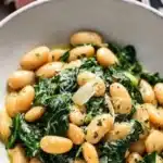 Creamy garlic butter beans served with fresh spinach in a bowl.