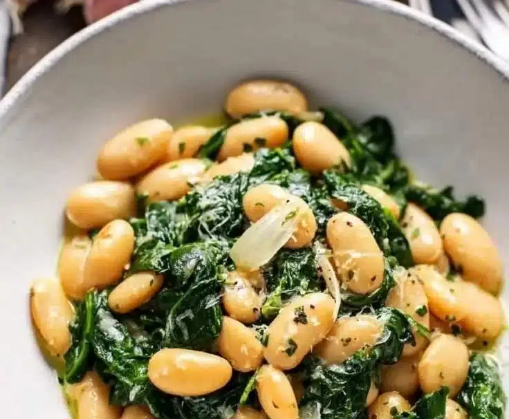 Creamy garlic butter beans served with fresh spinach in a bowl.