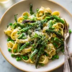 A delicious bowl of {{ $('Fetch Recipe Data').first().json["Main Keyword"] }} topped with fresh asparagus, green peas, and parmesan.