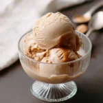 Three scoops of creamy coffee ice cream topped with a rich caramel drizzle in a glass dessert bowl.