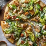 Sliced Chicken Caesar salad pizza topped with fresh romaine, grilled chicken, croutons, and creamy dressing.