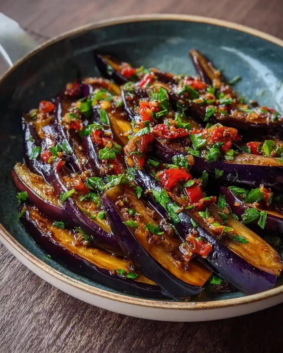 A close-up of a pan filled with {{ $('Fetch Recipe Data').first().json["Main Keyword"] }}, garnished with herbs and red peppers.